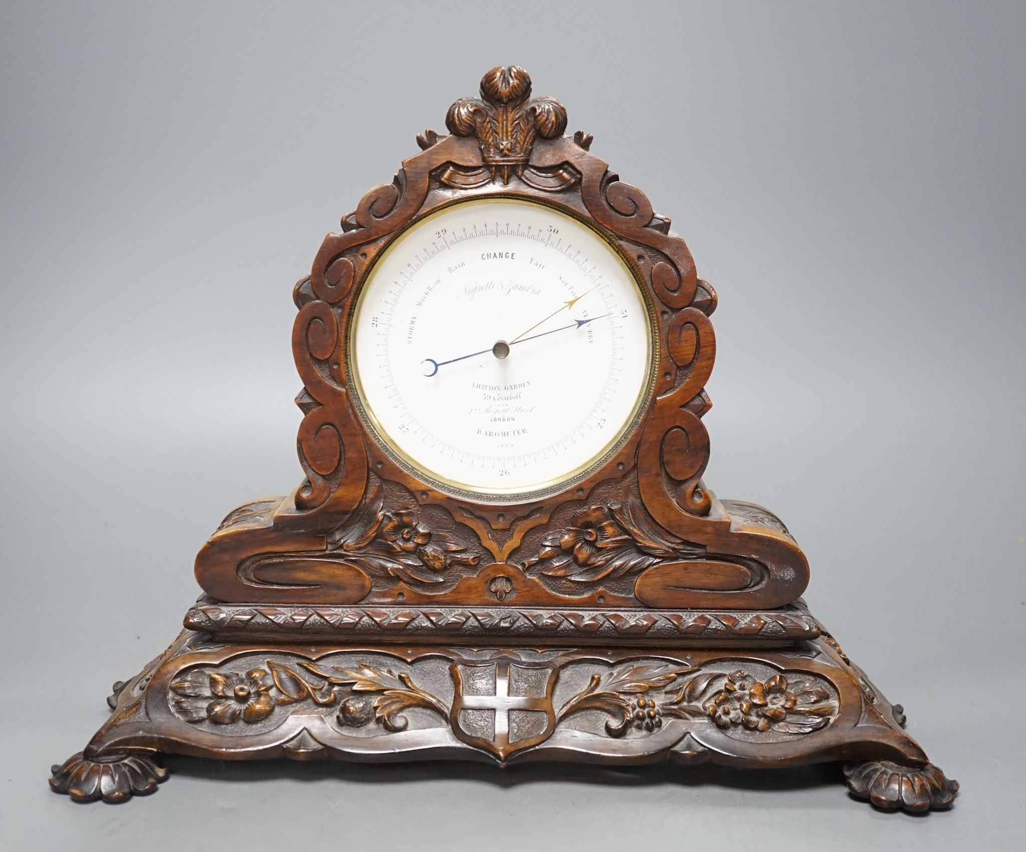 A late Victorian carved walnut aneroid mantel barometer by Negretti and Zambra, 34 cms wide